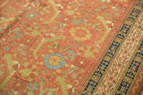 Angled detail of an antique Persian rug's worn pile, showing oversized Herati motifs and a navy border.