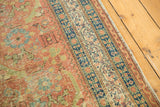 Angled detail of the antique Persian runner's terracotta field with pale green and navy Herati motifs.
