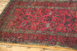 Angled detail of hand-knotted Persian Lilihan rug: raspberry field, floral vinery, worn edges.