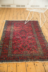 Vintage Lilihan rug end with tattered fringe, raspberry field, and teal floral palmette border.