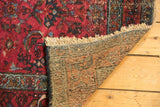 Vintage Lilihan rug corner with cream fringe, woven back, and wear across knot heads.