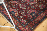 A vintage Lilihan rug corner showing cherry red floral patterns and the original side cord.