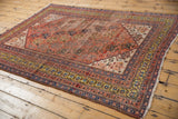 Antique Qashqai rug detail: saffron gold border, terra cotta field, germinating boteh, and edge wear.