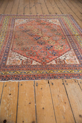 Antique Qashqai rug end with tattered fringe, saffron gold border, and subdued terra cotta field.