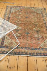 Distressed vintage Malayer rug's field with allover terra cotta and seafoam potted plant motifs.
