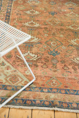 Distressed vintage Malayer rug showing abrash, terra cotta field, and worn blue, green motifs.