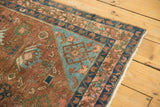 Distressed texture and fringed corner of Malayer rug, with terra cotta and seafoam green patterns.