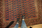 Staggered brick red paisley botehs on navy field with a chocolate bronze geometric border.
