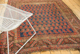 Antique Kurdish rug's chocolate bronze serrated leaf border and navy field of brick red paisley botehs.