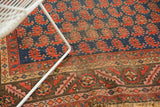 Antique Kurdish rug: navy field, bright red paisley botehs, chocolate bronze geometric border.