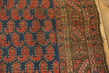 Antique Kurdish rug's navy field, red paisley botehs, geometric bronze border, and worn edge.