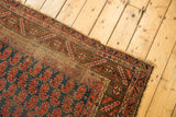 Kurdish rug detail: geometric serrated leaf border, navy and brick red paisley field, with wear and tatter.