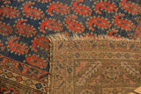 Antique Kurdish rug fold reveals navy, red paisley pile and geometric woven back with fringe.