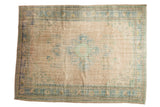 Distressed Oushak rug with faded peach field, blue-green medallion, floral bouquets, and spandrels.