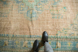 Distressed vintage Oushak rug's foundation showing through with faded aqua and beige patterns.