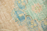 Distressed vintage Oushak carpet detail with even pile wear and faded aqua, beige, mint florals.