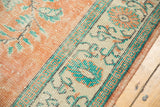 Vintage distressed Oushak carpet with worn tangerine field and mint green patterned border.