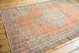 Distressed field with dusty orange peach tones and a pale royal blue scalloped medallion.