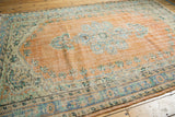 Distressed vintage Oushak rug corner, pale orange field and faded blue-green border.