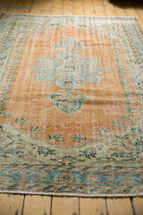 Distressed Oushak rug border in worn peach, mint green, and pale sky blue tones.