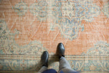 Textured distressed Oushak rug with apricot and faded blue, foundation visible.