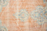 Distressed vintage Oushak rug texture with faded apricot, blue, and ivory tones showing visible foundation.