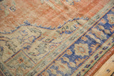 Worn pile texture of vintage Oushak rug, displaying dusty blue border and pale red field.