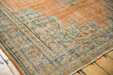 Ornate distressed border of vintage Oushak rug in pale tangerine, ivory, mint, and sky blue.