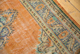 Distressed vintage Oushak rug corner revealing tangerine pile wear and ornate blue-green border.