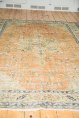 Distressed vintage Oushak rug showcasing low pile, foundation, and serrated border in apricot, ivory, navy.