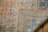 Distressed Oushak rug: textured low pile, exposed foundation, with terracotta and blue hues.