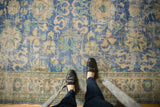 Distressed vintage Oushak rug with low shorn pile, visible foundation, and blue, mint, beige floral designs.