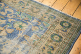 Detail of distressed Oushak carpet pile showing worn sky blue, mint green, and beige curvilinear motifs.
