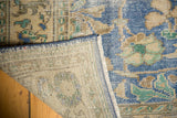 Distressed Oushak corner shows low sky blue floral pile and light beige foundation.