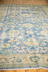 Distressed Oushak carpet surface with low shorn pile in sky blue, ivory, and mint.