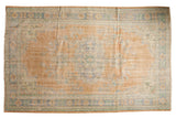 Vintage distressed Oushak carpet, oblong floral medallion, tangerine, blue, and ivory hues. 5'11