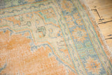 Distressed Oushak rug pile with visible knot heads, muted apricot, mint, ivory tones, and fringed edge.