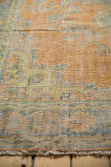 Low pile texture of distressed vintage Oushak rug, showing faded apricot and mint patterns.