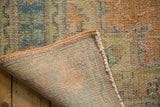 Detail of a vintage Oushak rug showing low pile, exposed foundation, and secured orange edge.