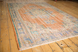 Textured low pile and distressed apricot, sky blue, ivory hues on a vintage Oushak rug.