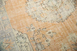 Oushak carpet section with distressed apricot field, detailed potted plant motif and scalloped edge.