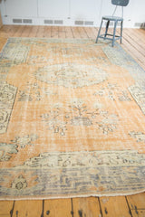 Worn apricot field meets muted blue-grey geometric border on a vintage distressed Oushak rug.
