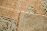 Vintage distressed Oushak rug corner, showing secured side binding and woven foundation.