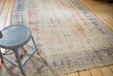 Distressed Oushak rug's textured pile, showing pale red, ivory, and faded blue floral motifs.