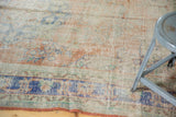 Distressed Oushak carpet's faded royal blue border and worn floral field with visible texture.