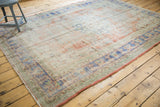Distressed Oushak carpet with worn texture and faded pale red, ivory, and blue tones.