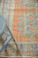 Worn pile of distressed vintage Oushak runner showing faded tangerine orange, blue, and mint.
