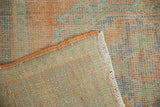 Distressed Oushak rug pile, terracotta, blue, mint, secured side, and faint foundation visible.
