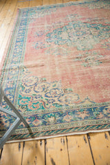 Distressed blush rose Oushak rug corner showing faded floral motifs and exposed foundation.