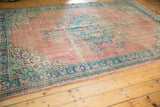 Angled view of the distressed blush rose field on a vintage Oushak carpet.
